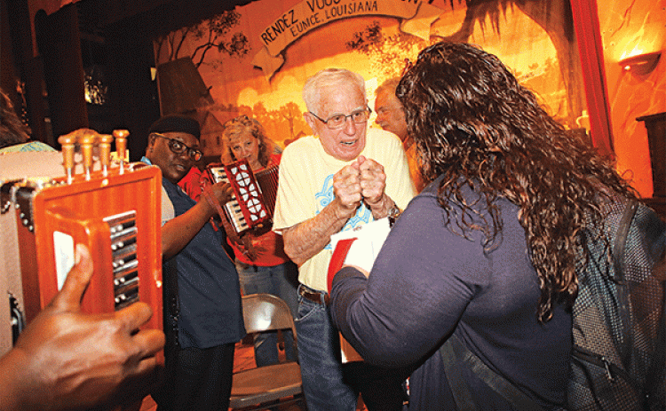Eunice musician Jerry DeVillier shows how to squeeze an accordion to a tour group member  on Tuesday at the Liberty Theatre. Alliance of National Heritage Area members are Acadiana this week. (Photo by Harlan Kirgan)