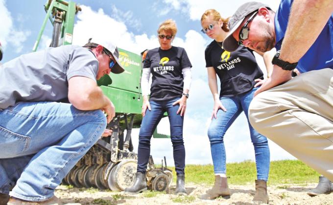 Rick Zaunbrecher, far left, explains how rice is being planted to Nan Wallis, second from left, and Lindsey Beard, second from right, both of Wetlands Sake, and Dustin Harrell, resident coordinator of the Rice Research Station and former LSU AgCenter rice specialist. Zaunbrecher, manager of the Foundation Seed Program at the H. Rouse Caffey Rice Research Station, planted the rice to be sold to Wetlands Sake to make its products at the New Orleans brewery. (Photo by Bruce Schultz/LSU AgCenter)