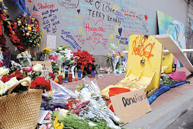 Flowers are placed Saturday, Jan. 4, 2025, at a memorial site on Bourbon Street in New Orleans near where 14 people were killed early Wednesday in a terrorist attack. The large yellow barrier is one of four that were placed on each side of hydraulic gate installed across Bourbon Street a day after Shamsud-Din Jabbar sped down three blocks before crashing and being killed in a shootout with police. (Greg LaRose/Louisiana Illuminator)