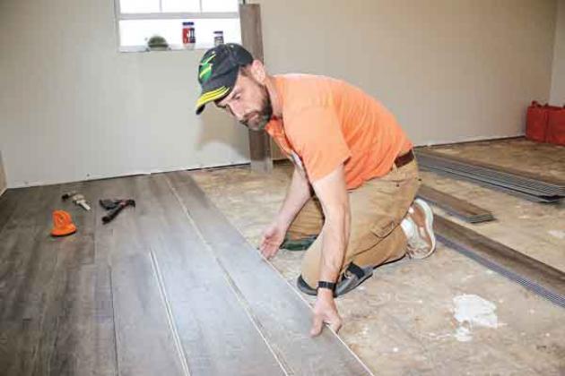 Ron Farney, of  Bloomington, Indiana, installs flooring in the Church Point house.