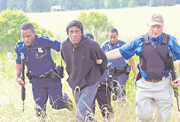 In this photo from April 2015, two-time escapee Theobegi Levier is escorted out of a field by Louisiana State Police troopers and members of the St. Landry Parish SWAT team following his capture in a field northwest of the Eunice Wal-Mart. Levier was once again the subject of a search on Thursday. (Photo by Claudette Olivier)