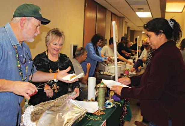 A Taster’s Choice ticket attendee Jalynn Cotton is wanting to try boudin at T-Boy’s booth in which Eric Soileau serves her a piece and watching on is Cathy Soileau.