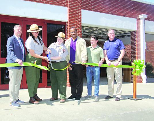Cutting a ribbon marking the reopening of the Prairie Acadian Cultural Center on Friday were, from left, Scott Fontenot  Eunice mayor; Laura McDonald and Lainey Binnix, park rangers; Herman Fuselier, parish tourism director; Justin Lemoine, executive director of the Atchafalaya National Heritage Area; and Dwight Jodon, Eunice Rotary Club member. (Photo by Harlan Kirgan)