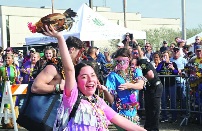 Joy shows in raising a rooster overhead in downtown Eunice on Mardi Gras.