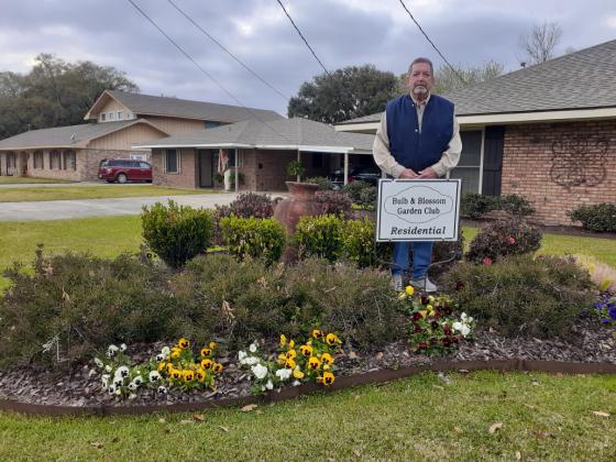 Keith Aucoin is pictured with the marker of Residential Garden of the Month presented by the Bulb &amp; Blossom Garden Club