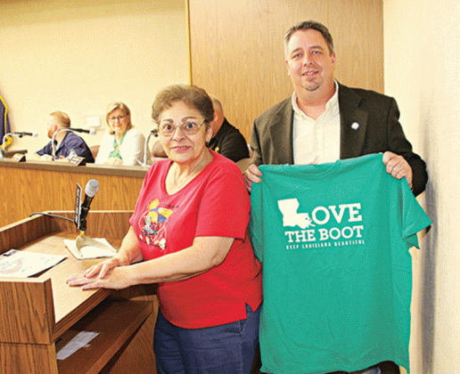 Eunice Mayor Scott Fontenot holds a T-shirt presented to him by Donna Baltakis, director of Keep Eunice Beautiful, at Tuesday’s Board of Aldermen meeting. Baltakis was at the meeting to remind the public about the Love the Boot cleanup day ion April 22. Volunteers are asked to register from 8:30 to 9 a.m. at City Hall. Bags, gloves, grabbers and a free T-shirt will be available. The volunteers are to return to City Hall at about 11 a.m. to drop off the garbage they collected and take a group photo. Seated i