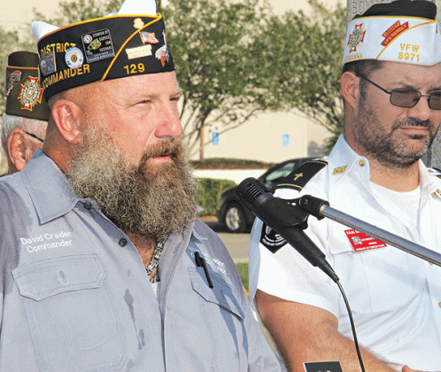 American Legion Post 129 Commander David Crader speaks at Monday’s ceremony.  At right is VFW Post  8971 member Paul Ganucheau. (Photo by Harlan Kirgan)