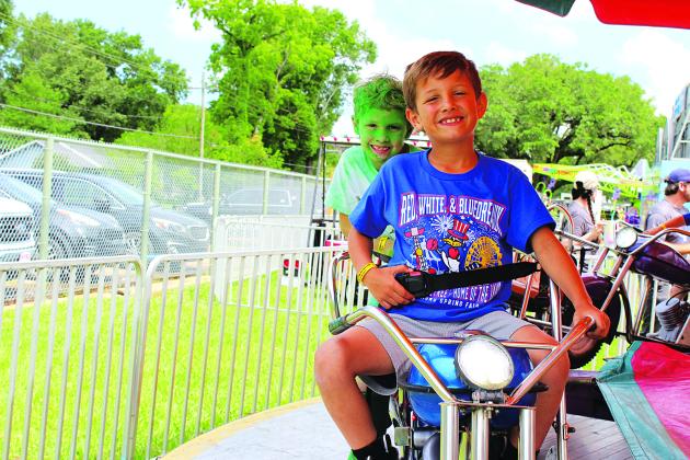 On a motorcycle fair ride are John Curtis, left, and Hudson Aguillard.