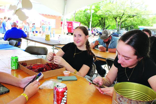 Eating boiled crawfish at the St. Edmund Spring Fair is Lorraine Ortego, left, and at right is Valerie Johnson.