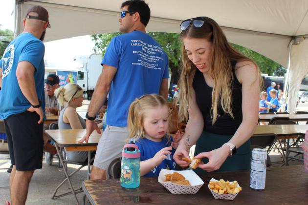 There were plenty of different foods available at the St. Edmund Spring Fair and Adeline Fontenot, 2, chose chicken strips and french fries. She is with her mother Gabbi Peloquin.