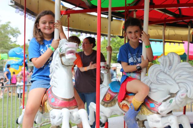 Averie Brown, left, and Isabelle Fontenot ride the carousel at the St. Edmund Spring Fair Saturday.