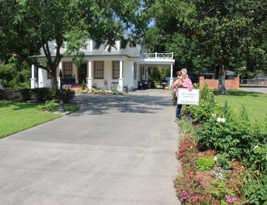 Kathy Manuel’s residence at 411 South 7th received the marker of Residential Garden of the Month from the Bulb &amp; Blossom Garden Club. The home features numerous landscpaed flowering beds of multi-colored verbena, calidiums, Austin David roses, day lilies, Skip Laurel, dianthus, Yarrow, salvia, Veronicas, Speed Well, Blue Spruce, lavendar, gardenias, larioppe, agapanthus, dahlias, azaleas, crepe myrtles, elms, box wood, and red buds.  Sadie, a 2 -year-old Dachshund, loves to be outdoors with her owner.
