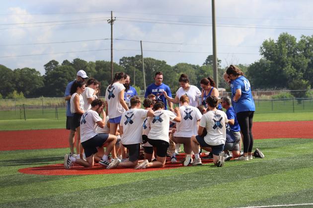 The St. Edmund classes of 2023 and 2004 pray after the game.