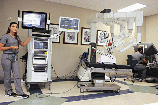 From left, are McKenzie O’Neal, and at far right, at the simulator surgeon console, Karl Lawrence, Clinical Territory Associate with Intuitive Surgical, presented and demonstrated Robotic surgical equipment to the Rotarians Wednesday.  (Photo by Myra Miller)