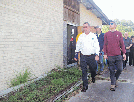 St. Landry Parish President Jessie Bellard, in the white shirt, leads a group on a walk around the vacant Moosa Memorial Hospital on Monday. He announced on Monday the building, vacant since 2006, will be demolished. At right in the red shirt is Phillip Cavins of Morgan and Morgan Land Preparation and Parish Council member Ernest Blanchard. (Photo by Harlan Kirgan)