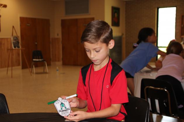 Zac Fruge, 8, shows off his Railroad Engineer badge at Vacation Bible School held at St. Thomas More Social hall. Children enjoyed arts and crafts as well as church reading lessons, outdoor games, activities, and snacks.