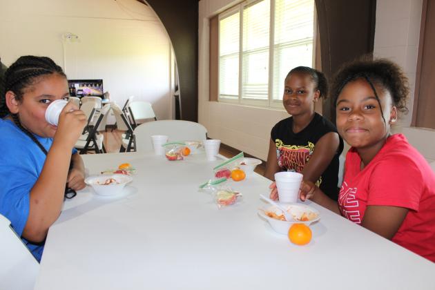 Children and teens, ages 1-18, can eat free breakfast and lunch meals offered at the Southeast Neighborhood Center. The ciy of Eunice and the Daisie Mae Foundation, Inc. is making this happen and will conclude on Aug. 9. Serving a lunch of spaghetti, oranges, apple slices, and milk at noon on Thursday were  Moses Andrus, Tanya Andrus, John Kenney and Orelia Lonnet. Pictured from left, are Anastyn Reed, 11, Anamya Shell, 13, and Jaden Reed, 13.