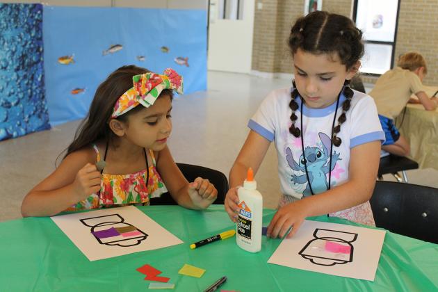 Hope Evans, 6, left, and Josie Touchet, 6, are coloring and crafting a coloring sheet, a lantern. The kids also crafted a wooden cut-out owl. They were able to paint their owl.