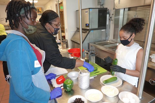 Chef Tasheena Butler from Delgado Community College helps students prepare their lunch during the Orleans Parish 4-H Healthy Living Workshop held on June 2. (Photo by Johnny Morgan/LSU AgCenter.)