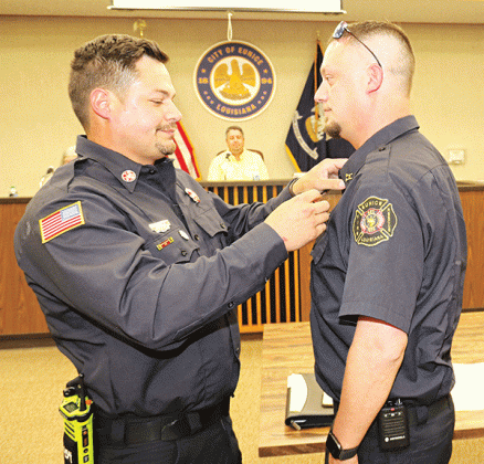 Chaise Brown, right, receives his badge as Eunice fire chief from his brother Ben Brown, a Eunice firefighter/operator, at Tuesday’s Board of Aldermen meeting. In the background is Mayor Scott Fontenot. (Photo by Harlan Kirgan)