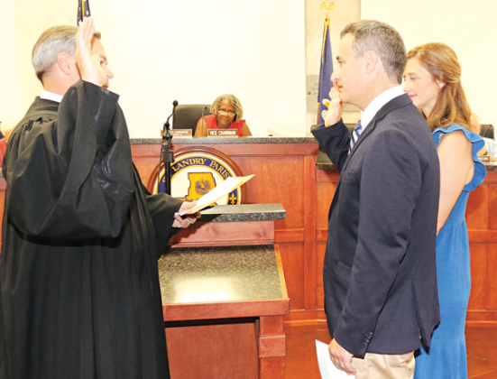 Dr. Zebediah Stearns recited an oath of office administered by District Judge Jason Meche at Wednesday’s St. Landry Parish Council meeting. With Stearns is wife, Christie. Seated, in the background is Nancy Carriere, Council vice chairwoman. (Photo by Harlan Kirgan)