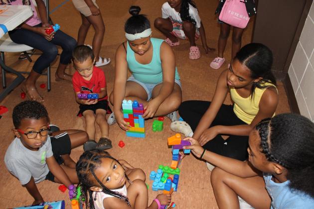 A group of kids are building with building blocks and Legos. The group of children are Remi Morgan, Boston Thomas, Jasiah Frank, Dominic Douglas, McKinley Douglas, and McKenzie Douglas.