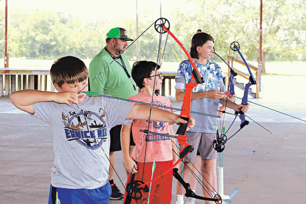 Above, from left, are Landry LeJeune, of Basile, Andre Guillory, of Eunice, and Max Daniel, of Baton Rouge, practice archery. Johnson is in the background.
