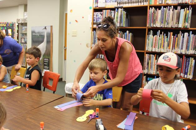 Creating their paper-chain snake craft at Story Time last Wednesday were Brenn Prudhomme, 4, and his older brother Blaine Theriot, 9. Their mother Jackie Prudhomme assists Brenn with his project.