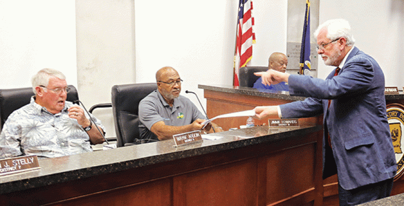 Gary McGoffin, right, an attorney representing the St. Landry Parish Council, hands out copies of a judgment to Parish Council members at a meeting Wednesday in Opelousas. Seated, from left, are Council members Wayne Ardoin, Jimmie Edwards and Jerry Red. The judgment is about a investigation by the Council into parish government employee terminations. (Photo by Harlan Kirgan)