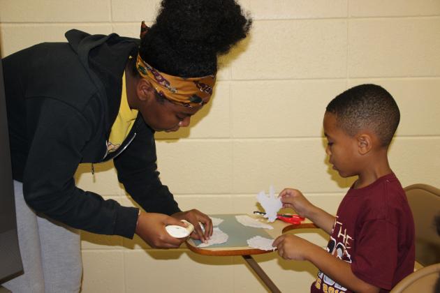 Zayiana Soileau, a volunteer, assist Leo Sam, 6, with a craft project during St. Mathilda’s Summer Youth Program. (Photo by Myra Miller)