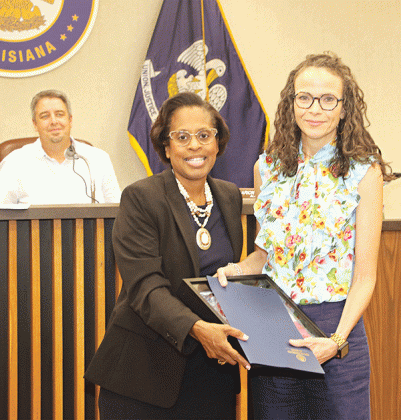 Eunice Alderwoman Germaine Simpson presents a flag and certificate to Paige Coutee in honor of Joseph “Joe” Coutee Jr. who operated Coutee’s Grocery. Looking on at left is Mayor Scott Fontenot. Turn to Page 10 for more photos from Tuesday’s city meeting. (Photo by Harlan Kirgan)