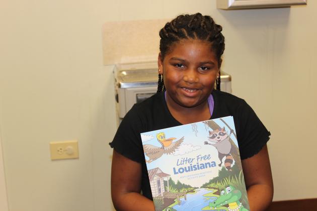 Caselynn Poullard, 9, receives A Litter Free Louisiana activity booklet at the library Wednesday.