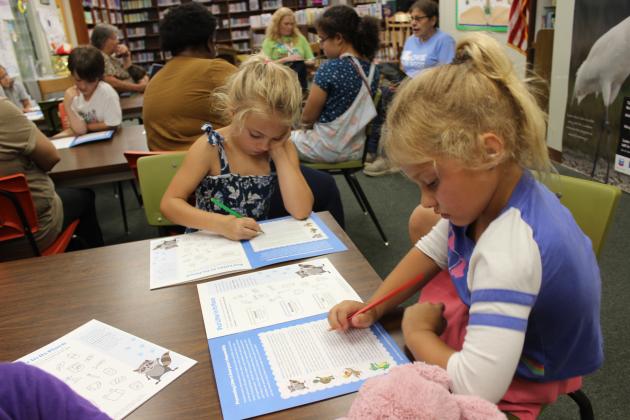 Kathryn Newsom, left, and Caroline Newsom read their activity booklet.