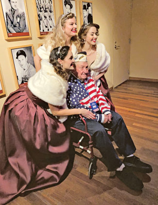 Richard has his photo taken with the National WWII Museum’s Victory Belles, a vocal trio that performs music from the 1940s. Richard visited the museum last year for the 80th anniversary of the attack on Pearl Harbor, and he was the only survivor to attend the event. (Photo courtesy of Connie Figueron)