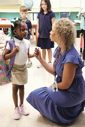First-grade teacher Arien Harper greets one of her students, Valynn Edwards, on her first day of school.  Looking on are Jackson Guillory and Aria Faulkner, also in Harper’s class. (Photo by Amy Myers)
