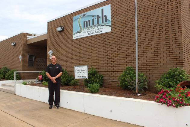 Dean Deshotel, a volunteer member of the Bulb &amp; Blossom Garden Club, presented the marker of Business Garden of the Month to Dr. Jason Smith of Smith Chiropractic &amp; Wellness, LLC located at 200 N. 2nd. The business features flowering landscaped beds of Knock out roses, azaleas, Pittosporum, Lily of the Nile, sasanquas, vinca, dianthus, and day lilies.