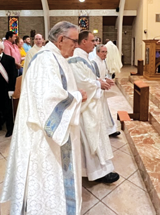 The Rev. Mitch Guidry, center, processes into Our Lady, Queen of All Saints Church. Also pictured are Deacon Chuck Ortego (left) and Deacon Ben Soileau (right). (Photo by Tony Marks/Ville Platte Gazette)