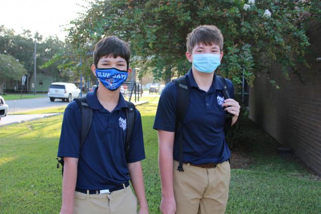Ash Pierrotti, seventh grader, and Landen Marcantel, eighth grader, arrive at St. Edmund for their first day of classes Monday.