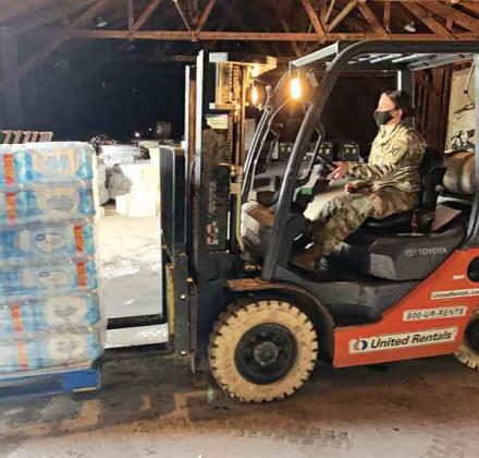 A Louisiana National Guardsman with the 769th Engineer Battalion loads a pallet of bottled water onto a high-water vehicle in order to be delivered to citizens in need during the winter storm at Camp Minden in Minden, on Feb. 19. The expansive infrastructure available on Camp Minden helps resolve large storage challenges presented during state emergencies. (U.S. Army National Guard courtesy photo from Louisiana National Guard)