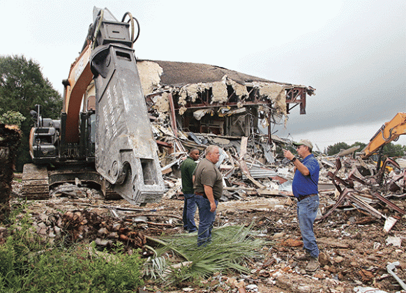 St. Landry Parish Government employees worked the weekend to demolish the second story of the old Moosa Memorial Hospital From left, are Eric Chisely, building maintenance supervisor; Jessie Bellard, parish president; and Todd Darbonne, fleet manager. They are by the shear tool used to cut through steel at the old hospital. (Photos by Harlan Kirgan)