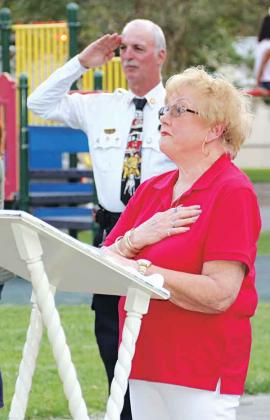 Evelyn Stringer, president of Woodmen Life Chapter 243, and Eunice Fire Chief Mike Arnold salute the flag at Saturday’s ceremony. (Photo by Harlan Kirgan)