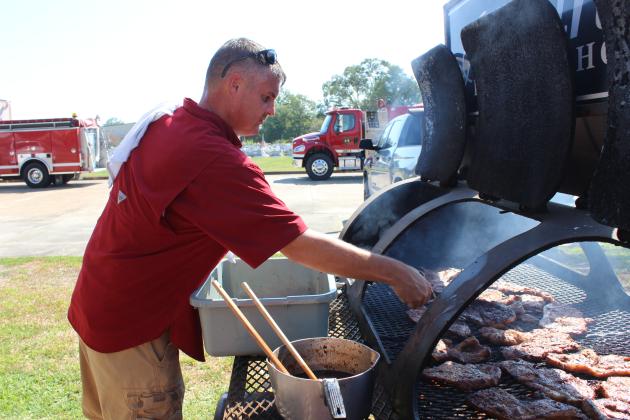 A volunteer cook, David Morgan, is at a BBQ pitt at Ardoin’s Funeral Home’s annual 911 first responders BBQ plate lunches.