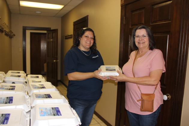 Chrissie Menard of Ardoin’s Funeral Home hands a plate lunch to Sherry Clark, secretary to the chief of police. Two hundred free plate lunches were prepared for all first responders.