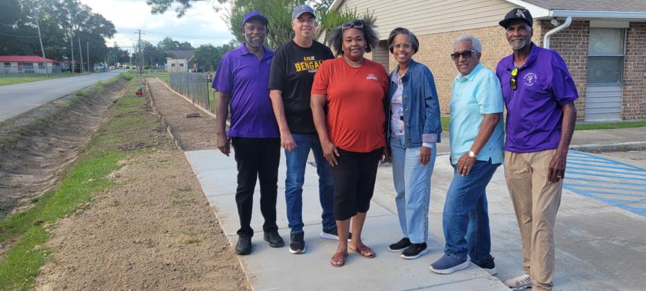 Satellite Social members, Mayor Scott Fontenot, Council woman Germaine Simpson on newly constructed sidewalk in front of Good Hope Apartments