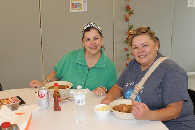 Jamie Smith, left, and Alicia G. Bielstein enjoy gumbo and potato salad at the church bazaar at St. Thomas More Catholic Church.
