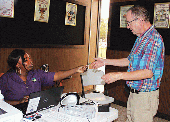 Trovette Matt, an employee with the Registrar’s of Voters Office, hands back Marcus N. Fontenot’s drivers license Tuesday morning at Eunice City Hall during early voting. (Photo by Myra Miller)