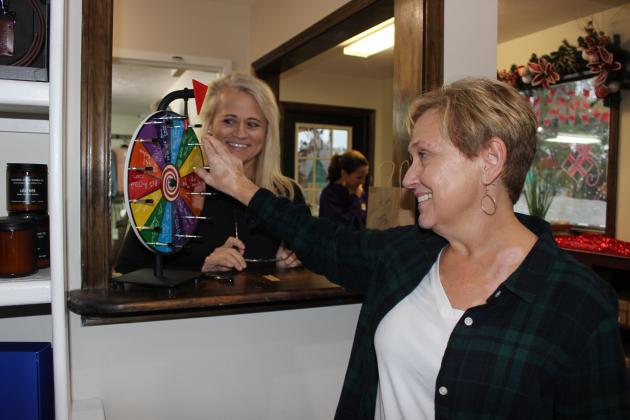 Spinning the wheel for a discount or door prize at Old Town Dude is Mona Pierrottie. Tonya Fortson, an employee, watches her spin.