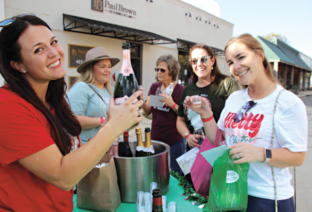 Greta Fontenot was in charge at one  of many sipping stations along South and North 2nd Street in Eunice during a Sip and Stroll event held Saturday. Fontenot pours a sample of one of the wines to Anne Marie Habetz. 