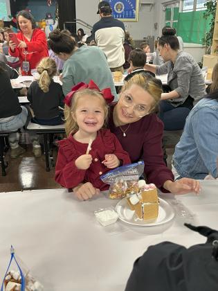 Remi Moore and Tori Matte work together on a gingerbread house at Highland Early Learning Center. Students and their families were invited to the annual event.