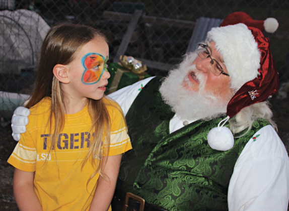Ellie Lyons, 7, and Santa have a nice chat at the Eunice Community Garden Christmas Festival Thursday evening. The Eunice Community Garden had its first ever Christmas Festival Thursday evening. There were over 15 booths at the Eunice Community Garden.  Many Eunice businesses, organizations, civic clubs, churches, LSUE and individuals were part of the event. Some booths gave free gift items and tokens, arts and crafts, while other booths held games and activities for kids. Randy Miller is the director of th